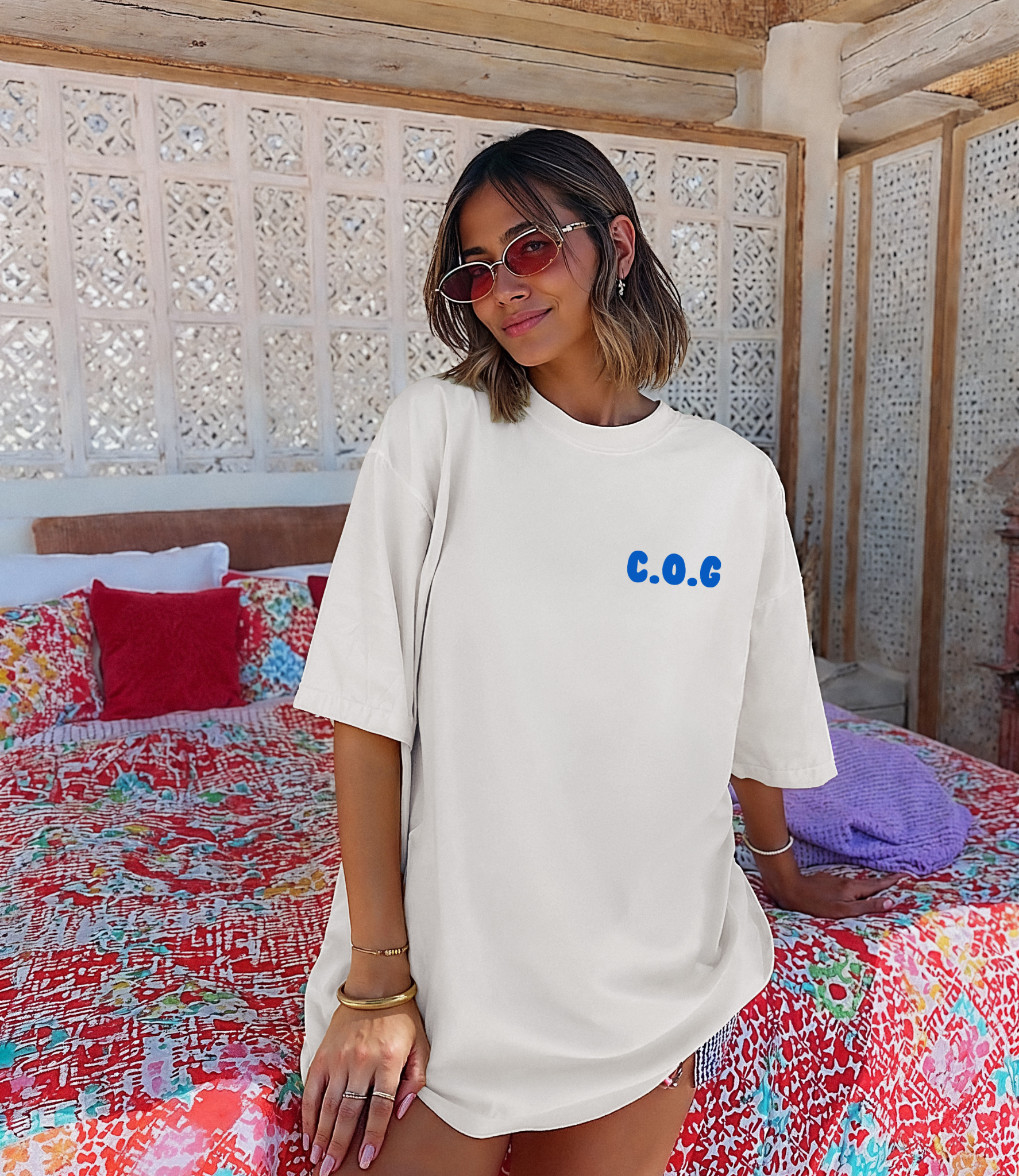 Woman wearing a white t-shirt with 'C.O.C' logo in a colorful room.