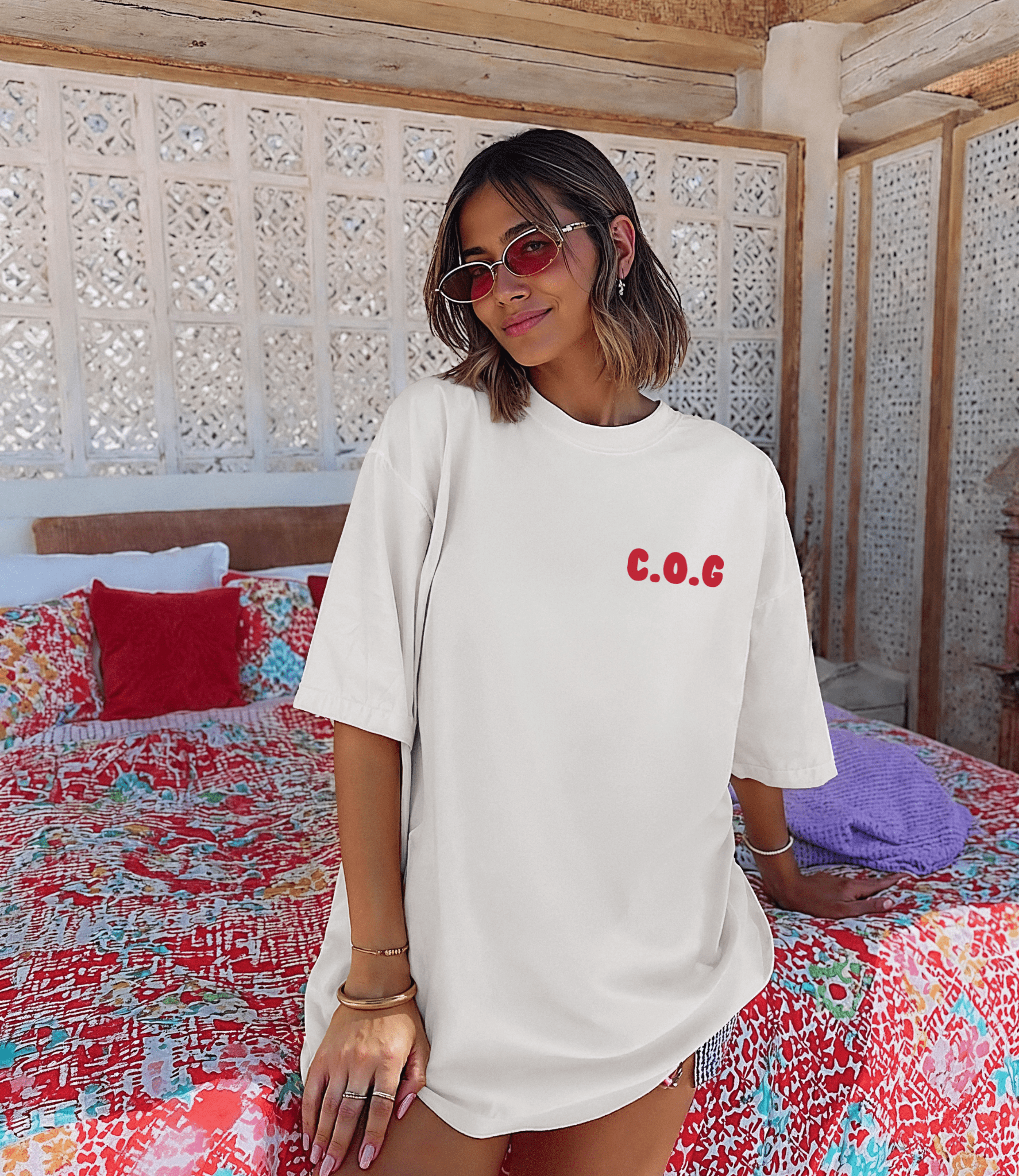 Woman wearing a white t-shirt with 'C.O.C' text in a colorful room.