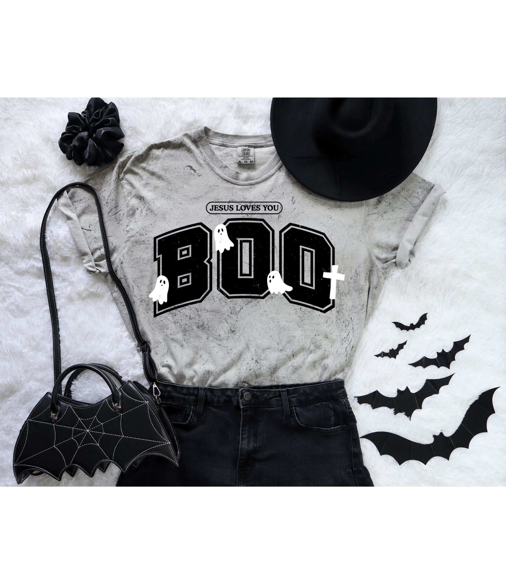 mineral wash Gray t-shirt with 'Jesus Loves You BOO' design on a white blanket with Halloween decor.