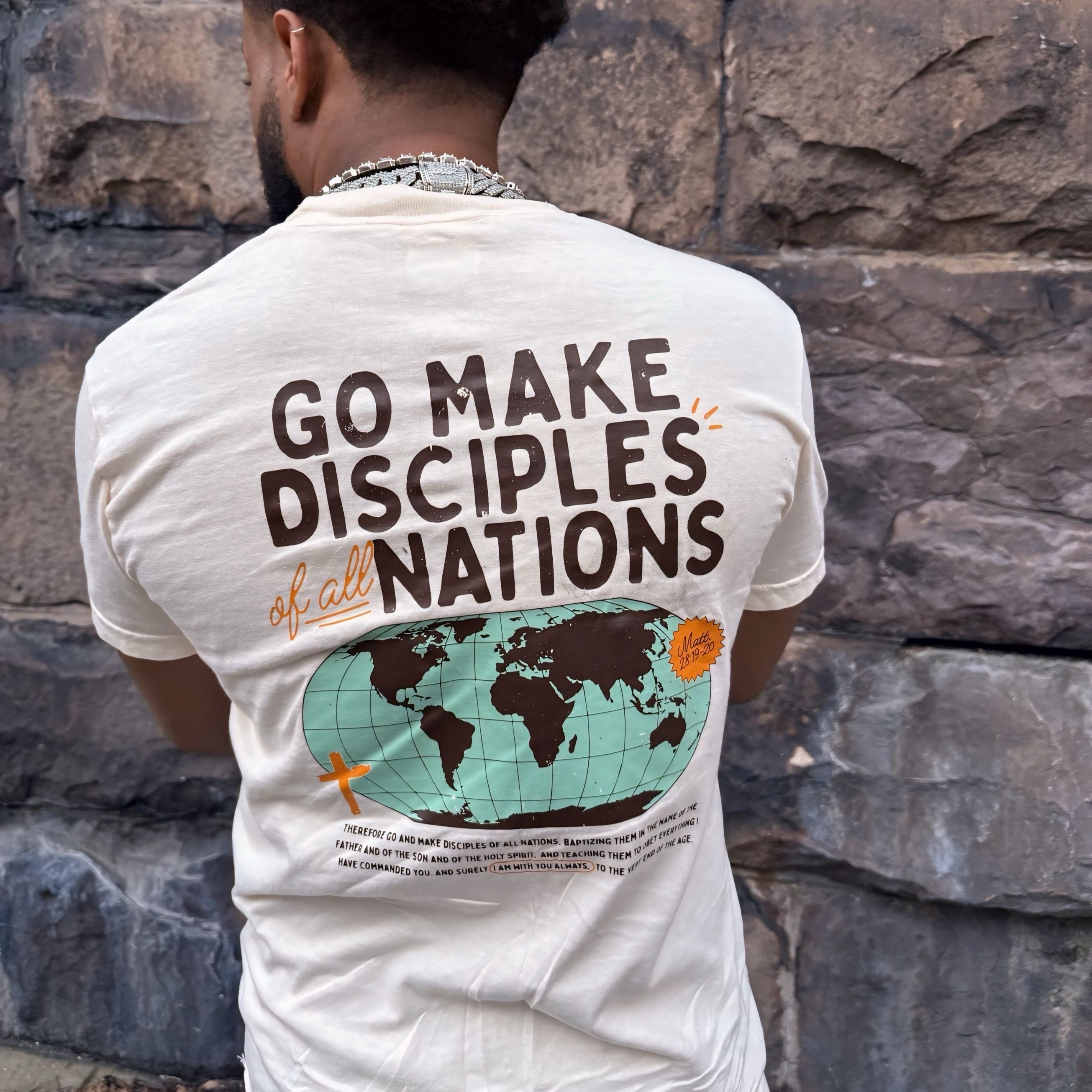 Person wearing a t-shirt with 'Go Make Disciples of All Nations' text and world map design.