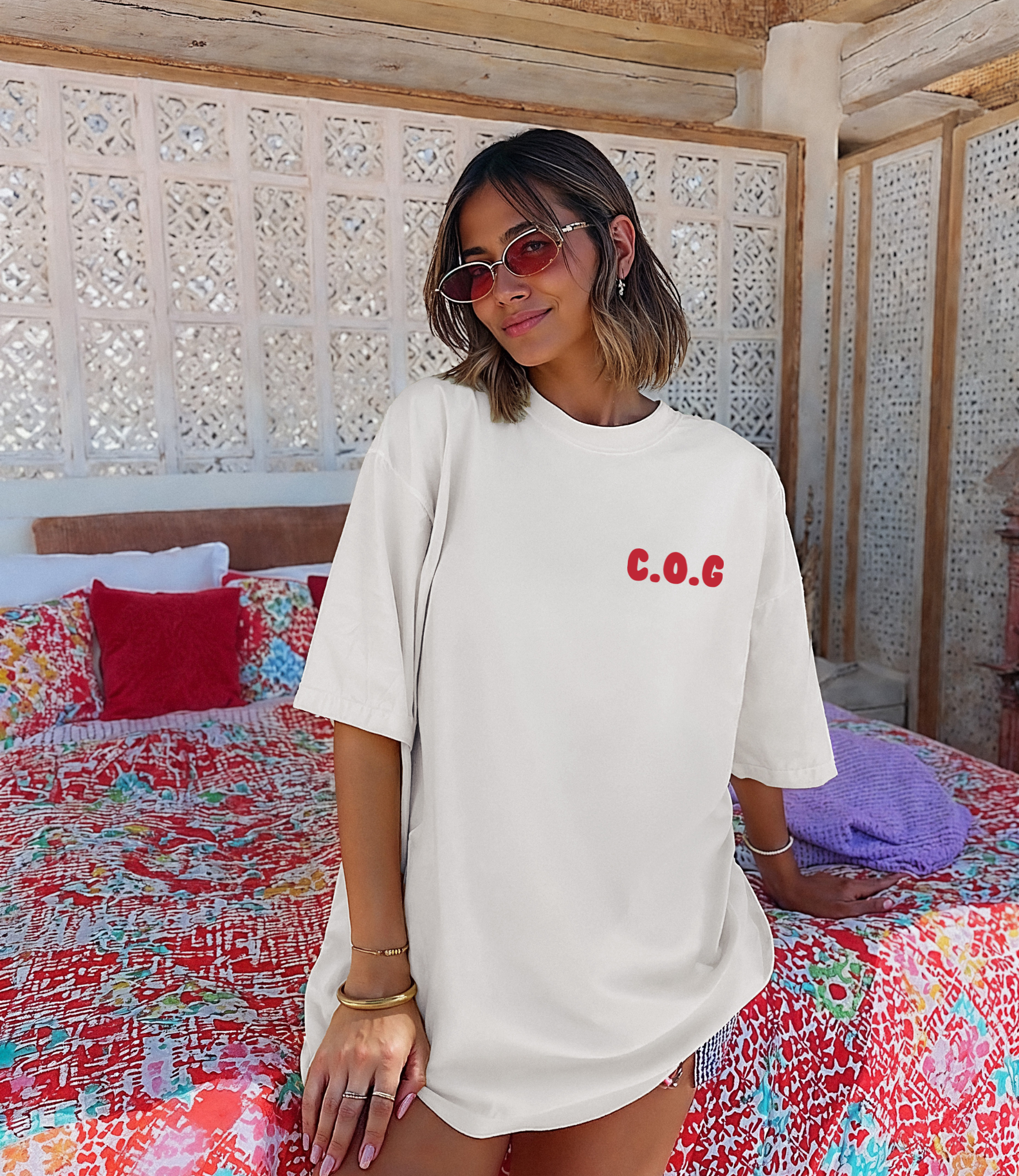 Woman wearing a white t-shirt with 'C.O.C' text in a colorful room.