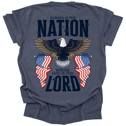Denim t-shirt featuring a bold eagle with outstretched wings, flanked by two American flags, and the text "Blessed is the Nation Whose God is the Lord," inspired by Psalm 33:12.