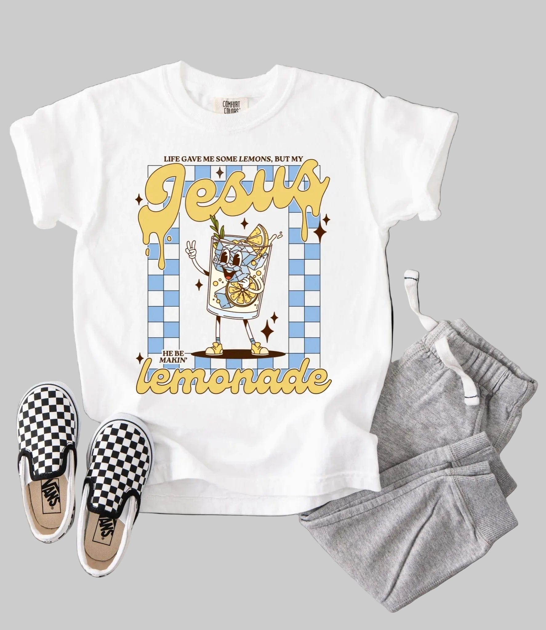 White t-shirt with cartoon character graphic, gray sweatpants, and checkered vans on a white background