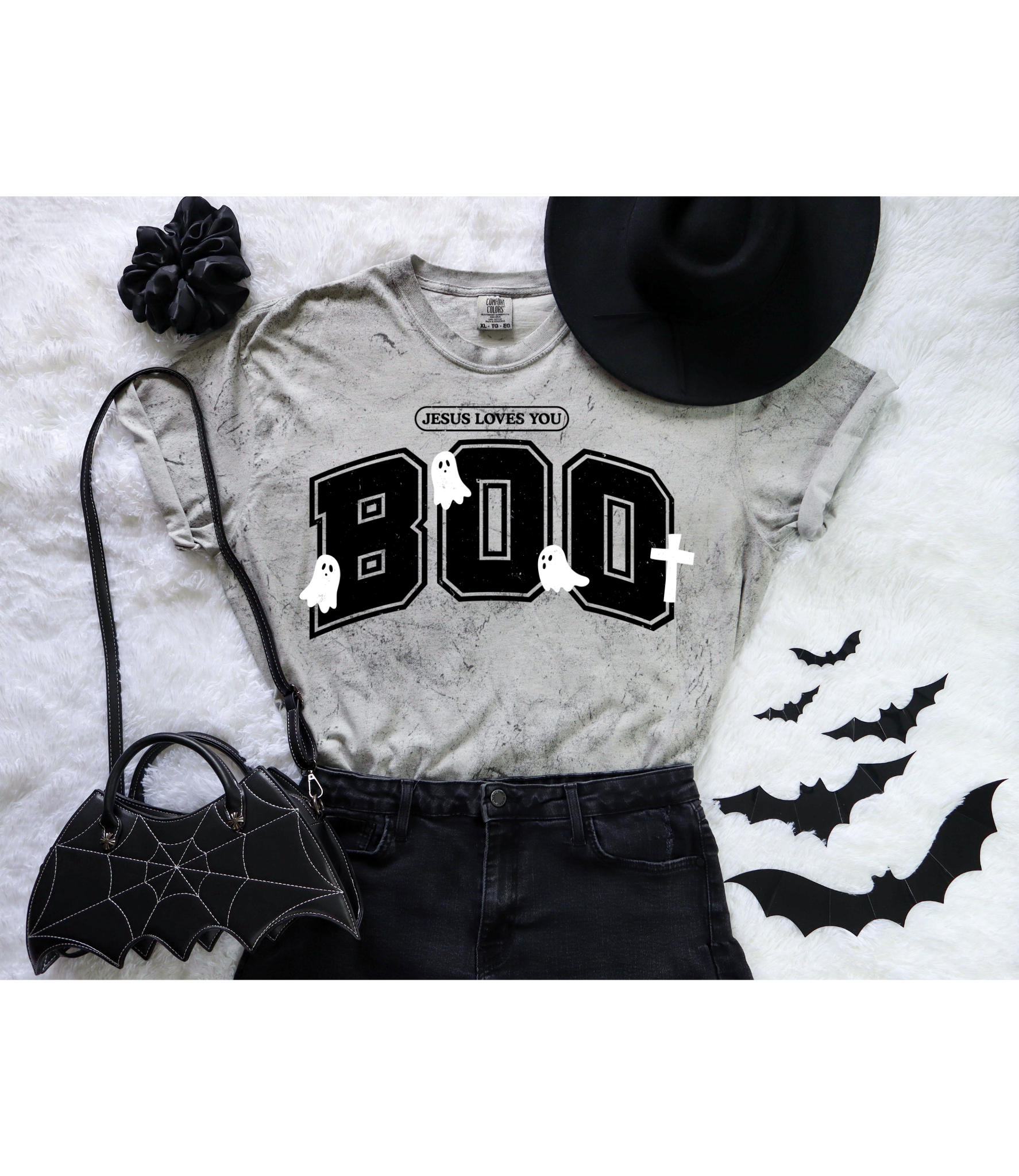 mineral wash Gray t-shirt with 'Jesus Loves You BOO' design on a white blanket with Halloween decor.
