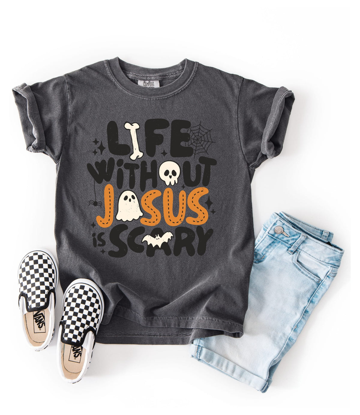 A dark gray graphic t-shirt with a Halloween-themed quote 'LIFE WITHOUT JESUS IS SCARY' in black, white, and orange lettering, styled in a flat lay with light blue denim shorts, black and white checkered slip-on shoes, and a white background.